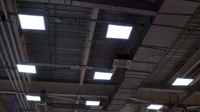 long pipes of hvac system and lamps hang on ceiling of big mall