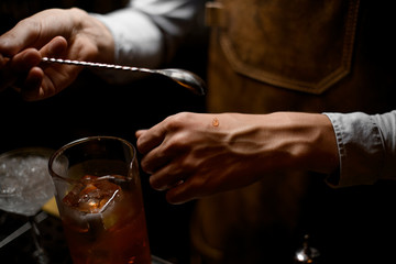 Close-up of bartender holding spoon for cocktails