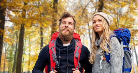 Fototapeta premium adventure, travel, tourism, hike and people concept - couple of travelers with backpacks over autumn park background