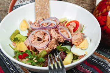 Fish salad of tuna, vegetables, tomatoes, peppers, onion rings, eggs, cabbage, lettuce and asparagus in the Georgian style. National cuisine