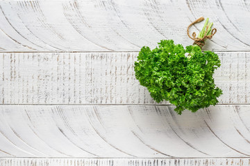Bunch of curly leaf parsley tied with jute rope, healthy vegetarian food. White wooden rustic background