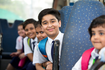 School children traveling in school bus looking at camera