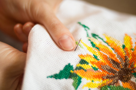  The process of working embroidery. Hands girls embroider pattern of flowers. Embroidery and cross stitch accessories. Close-up.