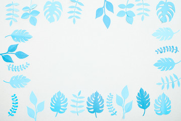 Fototapeta na wymiar top view of blue paper cut tropical leaves isolated on white with copy space