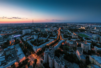 Night City Voronezh downtown or center panorama from above with illuminated road intersection, car traffic, modern business and residential buildings, aerial view