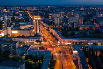 Fototapeta na wymiar Night City Voronezh downtown or center panorama from above with illuminated road intersection, car traffic, modern business and residential buildings, aerial view