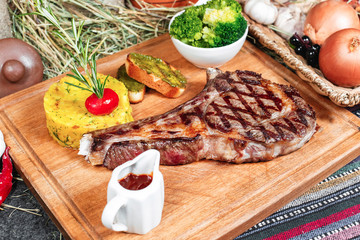T bon steak fried on charcoal. Grilled meat with mashed potatoes, broccoli, tomato sauce and croutons in oriental style, Georgian appetizer. National cuisine