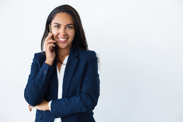 Happy businesswoman talking by smartphone. Attractive young woman in formal wear talking by cell phone and smiling at camera isolated on grey background. Connection concept
