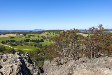 Aerial view of typical regional Australia rural landscape in the state of Victoria. Farmlands, houses, trees and country road. View from summit of Hanging Rock, VIC Macedon Ranges.