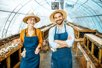 Portrait of a two happy well-dressed farmers standing in the hothouse on a farm for growing snails. Concept of farming snails for eating