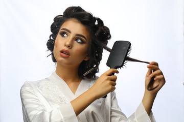  dreamy girl is combing her hair. Beauty and hair care concept. Beautiful girl in hair curlers...