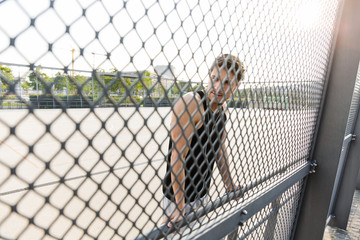 Photo of young man wearing earphones standing on sports ground during morning workout outdoors