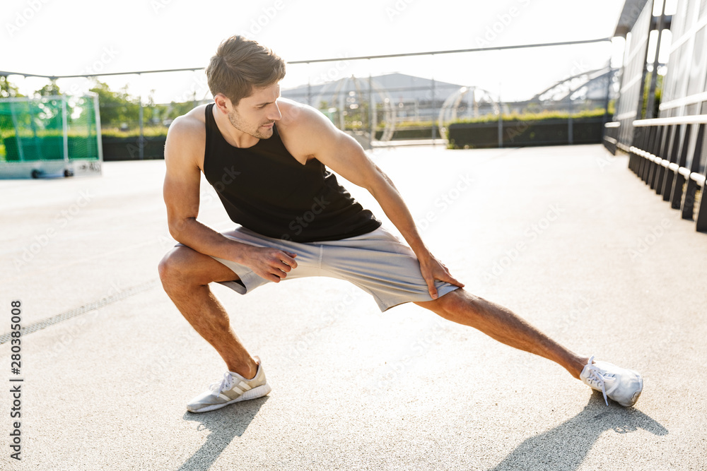 Poster image of brunette man training on sports ground during morning workout outdoors