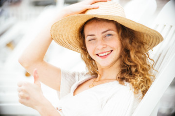 Beautiful ,elegant, teenager, with red hair and freckles,wearing a white dress and a hat, enjoy the seaside resort, watch in the distance the beautiful panorama covering her eyes with the palm of hand