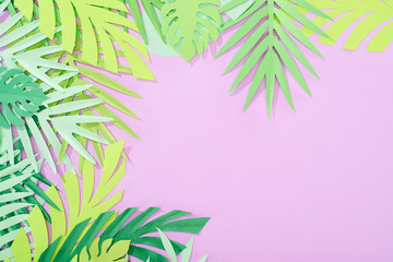 Fototapeta na wymiar top view of green paper cut tropical leaves on violet background with copy space