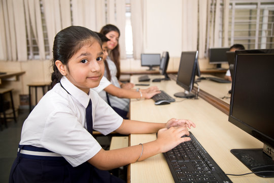 Indian teacher helping students at computer class
