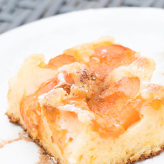 Delicious homemade apricot cake with cinnamon and powdered sugar on a white dishware. Tasty sheet cake with apricots.