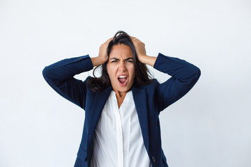 Emotional young woman screaming at camera. Portrait of shocked businesswoman holding hands on head...
