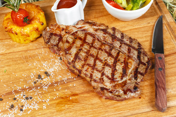 grilled beef steak according to Georgian recipe. Served with tomato sauce and fresh vegetable salad. National cuisine