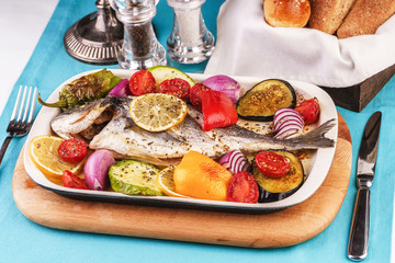 Mediterranean dish, Georgian recipe. Baked river fish with lemon, vegetables, pepper and grilled tomatoes with spices.