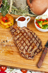 grilled beef steak according to Georgian recipe. Served with tomato sauce and fresh vegetable salad. National cuisine