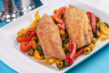 Grilled fish steak carp served with stewed chili peppers, olives, olives, greens and green pepper according to the Georgian recipe. Mediterranean Kitchen 