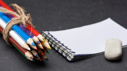 Colored sharpened pencils tied with a rope on the background of a notebook in blur.