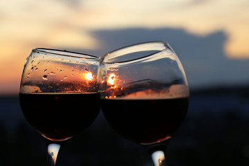 Two glasses with alcohol drinks on sunset background. Sun is reflected in glass, concept of celebration, romantic evening, love date, wine tasting
