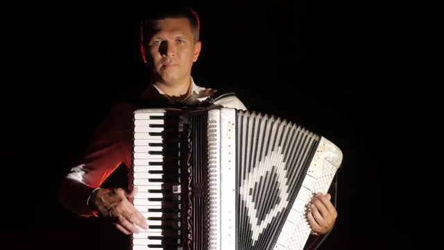 young accordionist plays the accordion masterly in the studio on a black background, isolated