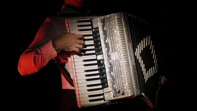 young musician virtuoso plays the accordion masterly in the studio on a black background,isolated,close-up