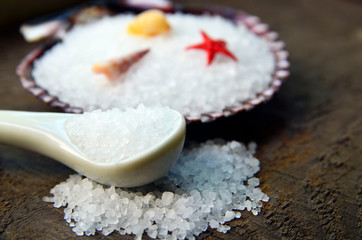 Fototapeta na wymiar Sea salt in a white spoon on old wooden background.Healthy eating,spa or beauty treatment concept.Soft focus.