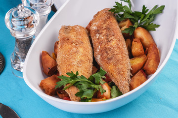Grilled fish steak is served in batter with braised and roasted potato wedges. Mediterranean cuisine, European dish