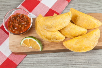 Tasty colombian food, fried empanada; photo on wooden background.