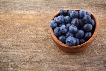 Fresh raw blueberries in the bowl on a wooden table.
