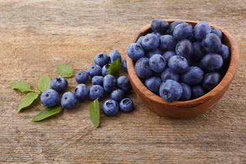 Fresh raw blueberries with leaves on white wooden background. Organic food