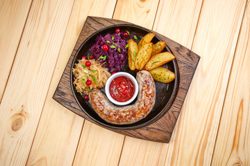 sausage with baked potatoes and salad on the wooden background
