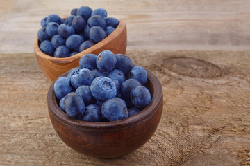 Fresh raw blueberries in the bowl on a wooden table.