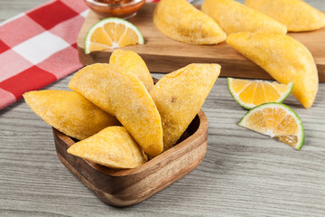 Tasty colombian food, fried empanada; photo on wooden background.