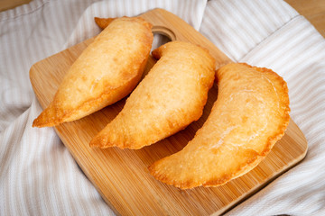 Three delicious fried panzerotto on a wooden chopping board. Typical food of Puglia, Italy