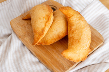 Three delicious fried panzerotto on a wooden chopping board. Typical food of Puglia, Italy