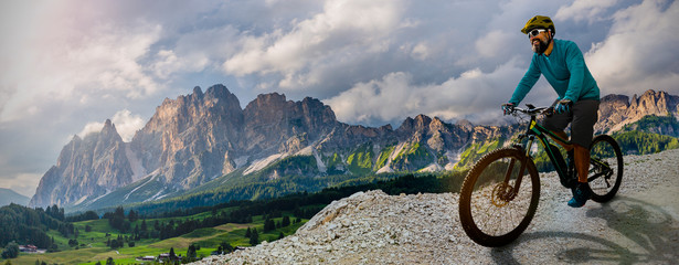 Man cycling on electric bike, rides mountain trail.  Man riding on bike in Dolomites mountains...