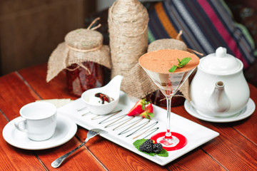 chocolate cake in a cocktail glass with nuts, sprinkled with sweet sauce with berries