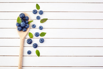 Fresh raw blueberries with leaves on white wooden background. Organic food