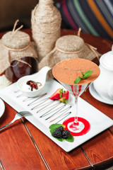 chocolate cake in a cocktail glass with nuts, sprinkled with sweet sauce with berries