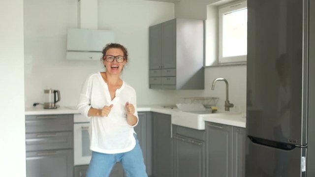 Portrait of a beautiful young woman dancing in her new kitchen after the renovation is completed. Real estate repair concept