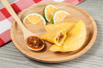 Tasty colombian food, fried empanada; photo on wooden background.