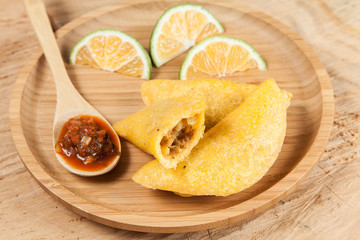 Tasty colombian food, fried empanada; photo on wooden background.
