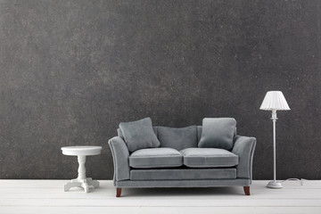 Modern grey sofa on grey wall background. Free space
