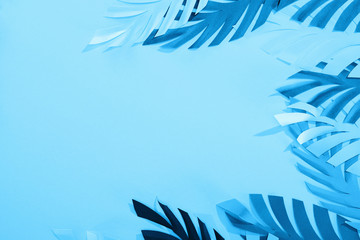 Fototapeta na wymiar top view of paper leaves on blue minimalistic background with copy space