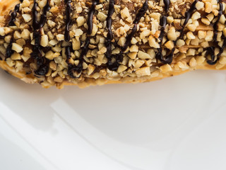 chocolate eclair sprinkled with nuts on a white plate